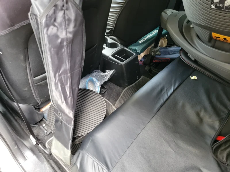 コンパクトカーの後部座席の足元や座席横にキャンプ道具を分散して積んだ様子