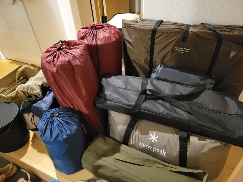 家族4人のキャンプ道具を玄関に並べた様子。スノーピークのテントバッグやインフレータブルマット、寝袋などが並ぶ